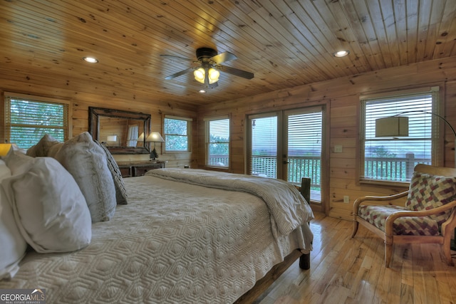 bedroom featuring light wood-type flooring, wood walls, wooden ceiling, and ensuite bath