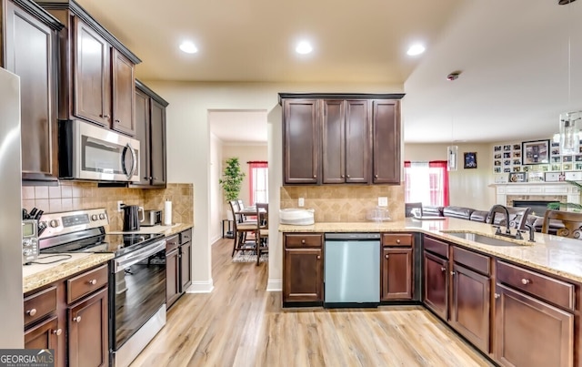 kitchen with light hardwood / wood-style flooring, hanging light fixtures, stainless steel appliances, backsplash, and sink