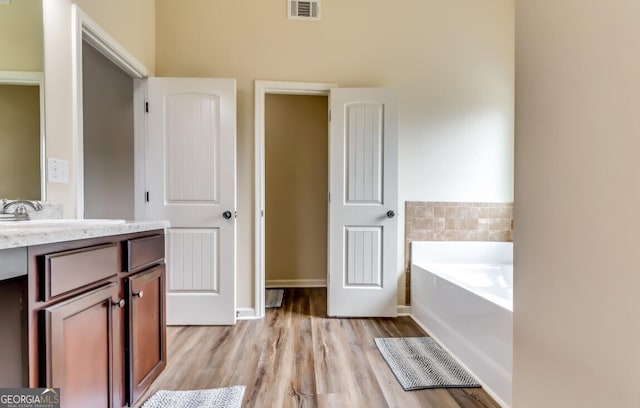 bathroom with vanity, a tub, and wood-type flooring