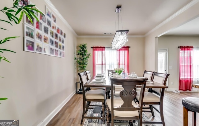 dining space featuring light hardwood / wood-style floors, a notable chandelier, and crown molding