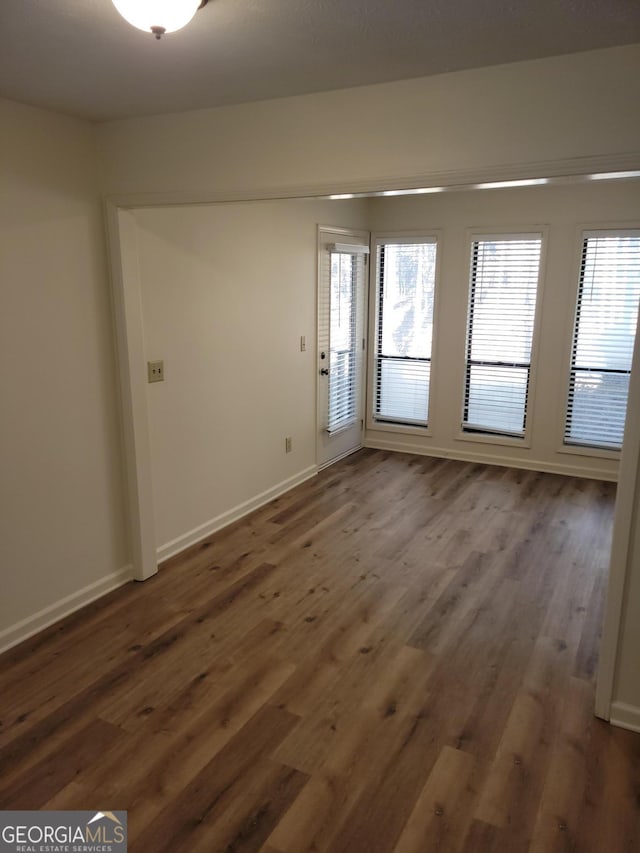 spare room with dark hardwood / wood-style flooring and plenty of natural light