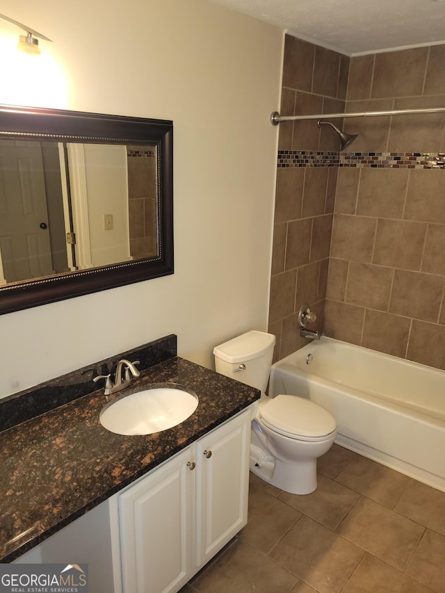 full bathroom featuring toilet, vanity, tile patterned flooring, and tiled shower / bath