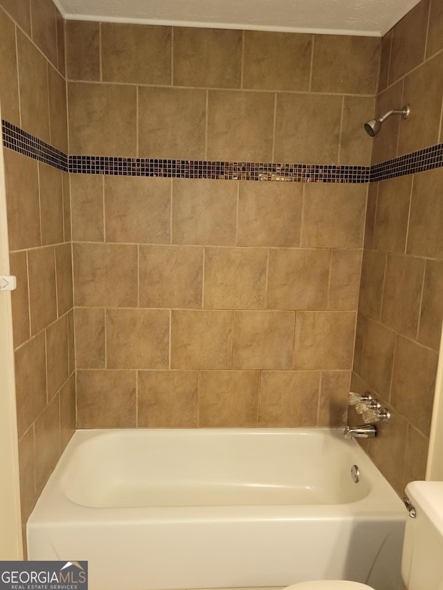 bathroom featuring toilet and tiled shower / bath combo