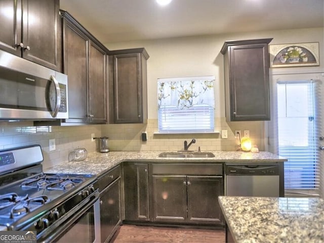 kitchen with light stone counters, dark hardwood / wood-style flooring, sink, and stainless steel appliances