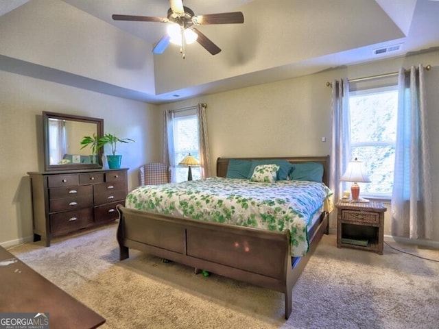 bedroom featuring a raised ceiling, ceiling fan, light colored carpet, and vaulted ceiling