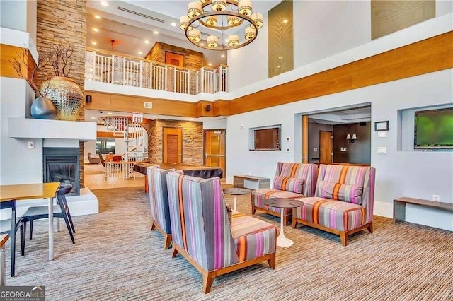 living room with a high ceiling, a chandelier, and a large fireplace