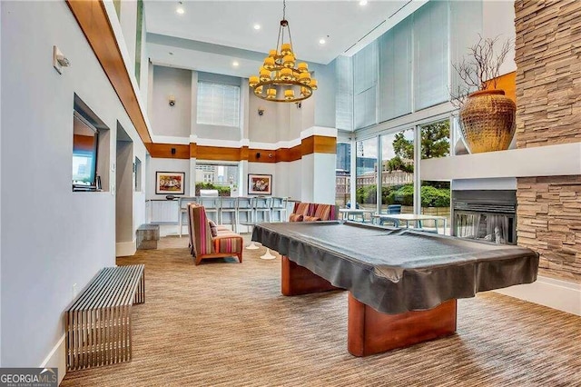 recreation room with a stone fireplace, a high ceiling, billiards, and a wealth of natural light