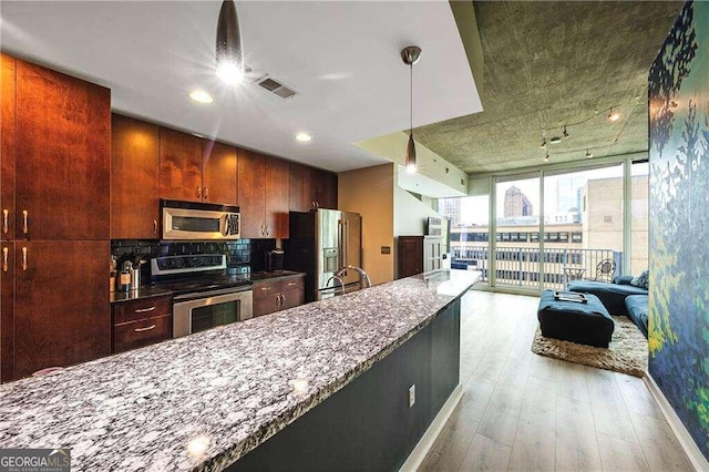 kitchen featuring backsplash, dark stone counters, appliances with stainless steel finishes, a wall of windows, and light hardwood / wood-style floors