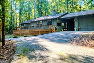 view of front of property with a wooden deck, an attached garage, driveway, and a chimney