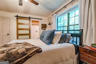 bedroom with a barn door and a ceiling fan