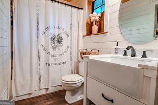 bathroom with toilet, vanity, shower / tub combo, and wood finished floors