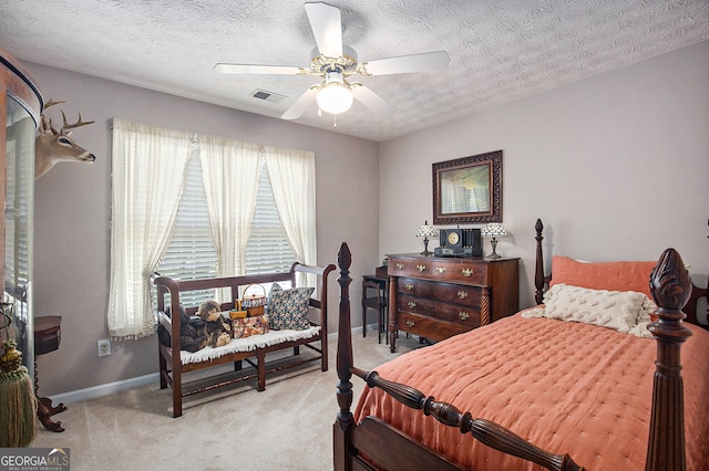 bedroom featuring ceiling fan, light colored carpet, and a textured ceiling