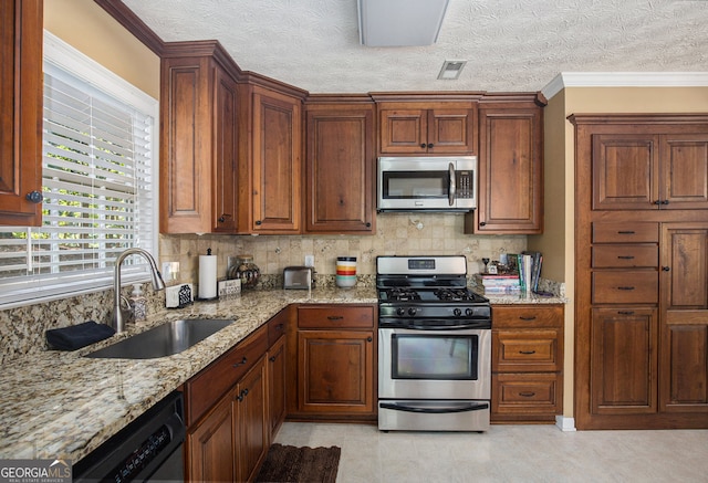 kitchen with sink, ornamental molding, a textured ceiling, appliances with stainless steel finishes, and light stone countertops