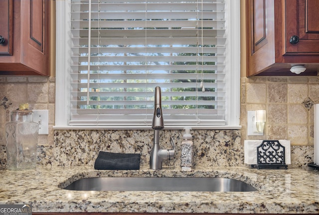 kitchen featuring sink, light stone counters, and tasteful backsplash