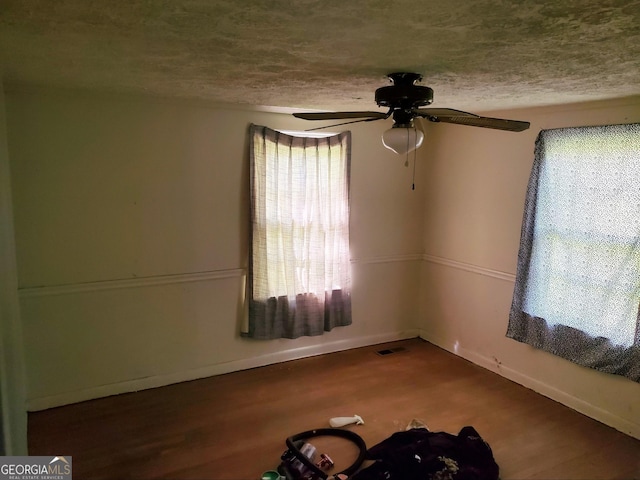 empty room with ceiling fan, hardwood / wood-style floors, and a textured ceiling