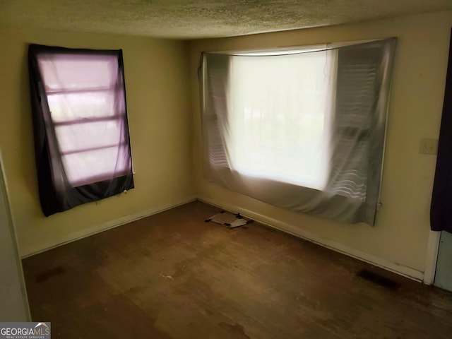 unfurnished room with a textured ceiling and dark hardwood / wood-style floors