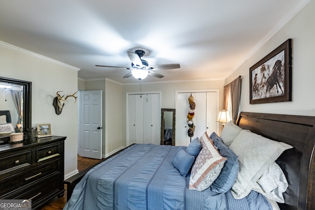 bedroom with ceiling fan, dark hardwood / wood-style flooring, crown molding, and multiple closets