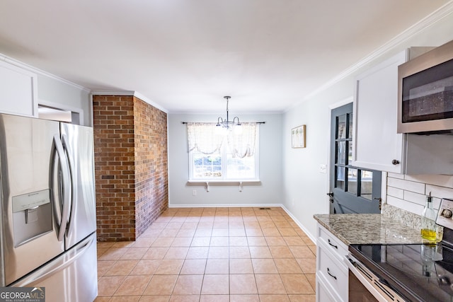 kitchen with light stone countertops, appliances with stainless steel finishes, an inviting chandelier, white cabinets, and hanging light fixtures