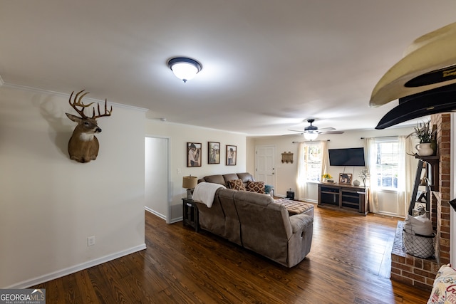 living room with dark hardwood / wood-style floors, ceiling fan, crown molding, and a fireplace