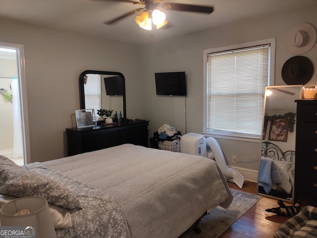 bedroom with ceiling fan, multiple windows, and hardwood / wood-style floors