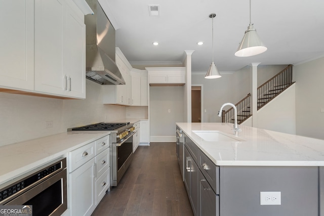 kitchen featuring sink, a center island with sink, wall chimney exhaust hood, white cabinetry, and stainless steel appliances