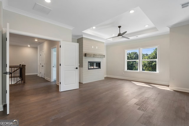 unfurnished living room with a tray ceiling, dark wood-type flooring, ceiling fan, and a large fireplace