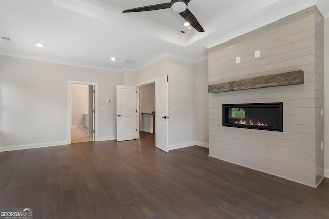 unfurnished living room with ceiling fan, a raised ceiling, ornamental molding, a fireplace, and dark hardwood / wood-style flooring