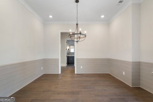 unfurnished dining area featuring crown molding, dark hardwood / wood-style floors, and a chandelier