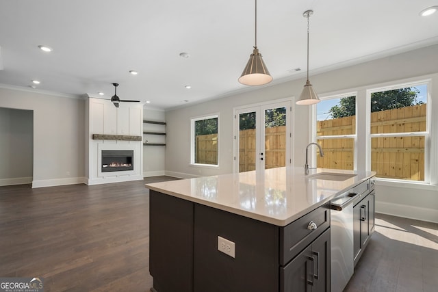 kitchen featuring a center island with sink, dark wood-type flooring, sink, and a large fireplace