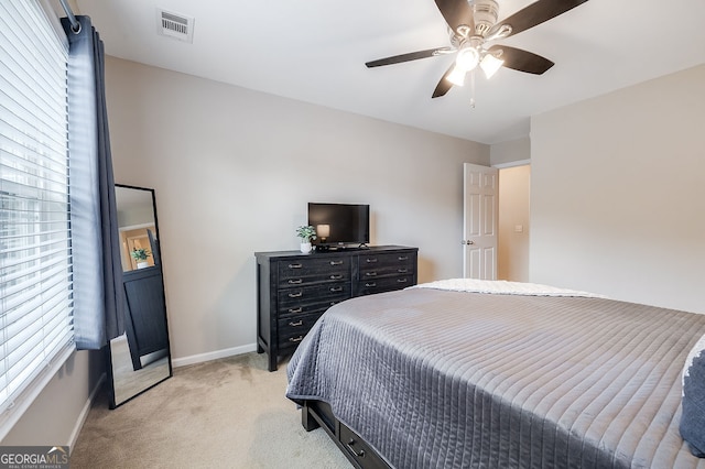 bedroom with multiple windows, light carpet, and ceiling fan