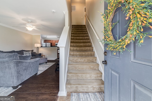 stairway with wood-type flooring, crown molding, and ceiling fan