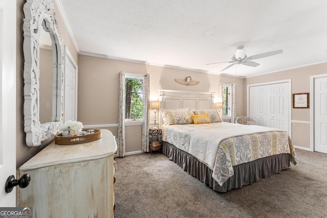 carpeted bedroom featuring ceiling fan, a textured ceiling, two closets, and crown molding