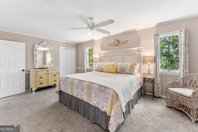 carpeted bedroom featuring a closet, ceiling fan, a textured ceiling, and crown molding