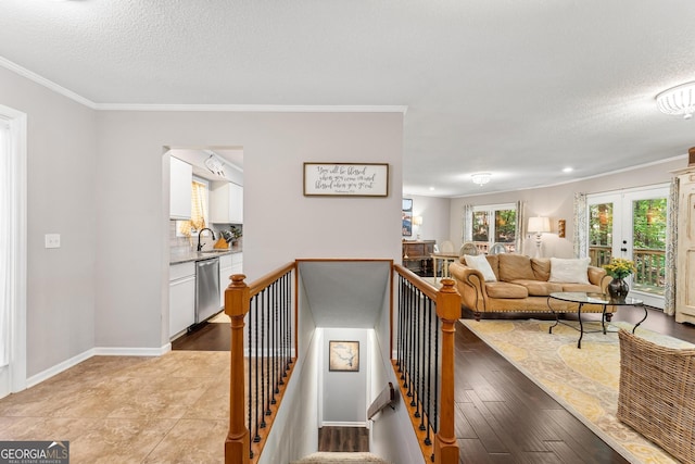 interior space featuring a textured ceiling, ornamental molding, sink, and light hardwood / wood-style flooring