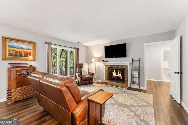 living room featuring a brick fireplace, a textured ceiling, and hardwood / wood-style flooring