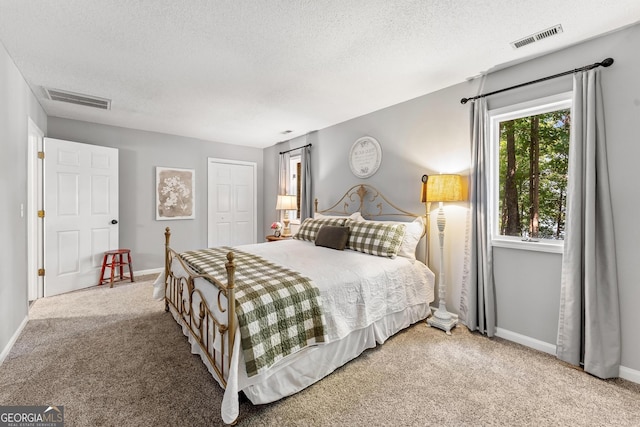 carpeted bedroom featuring a textured ceiling and a closet