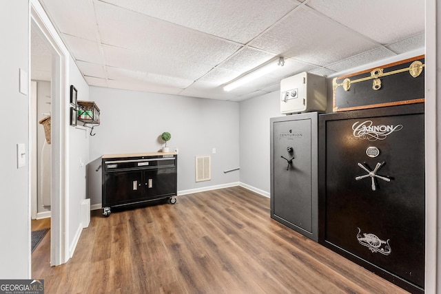 interior space with a drop ceiling and hardwood / wood-style flooring