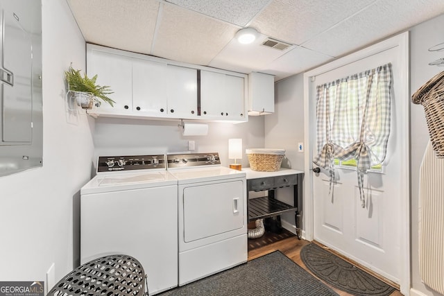 laundry room with washer and clothes dryer, cabinets, dark hardwood / wood-style floors, and electric panel