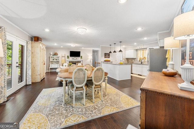 dining room featuring a tile fireplace, sink, dark wood-type flooring, and crown molding