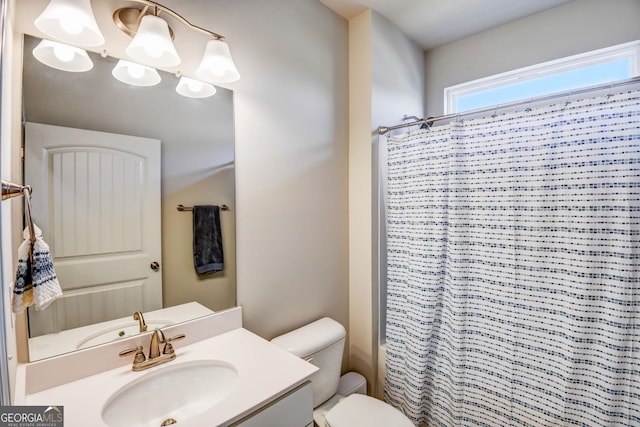 bathroom with walk in shower, vanity, and toilet