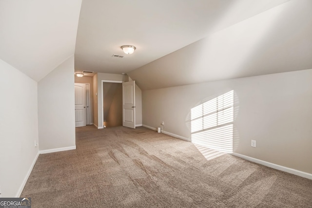 bonus room with light carpet and vaulted ceiling