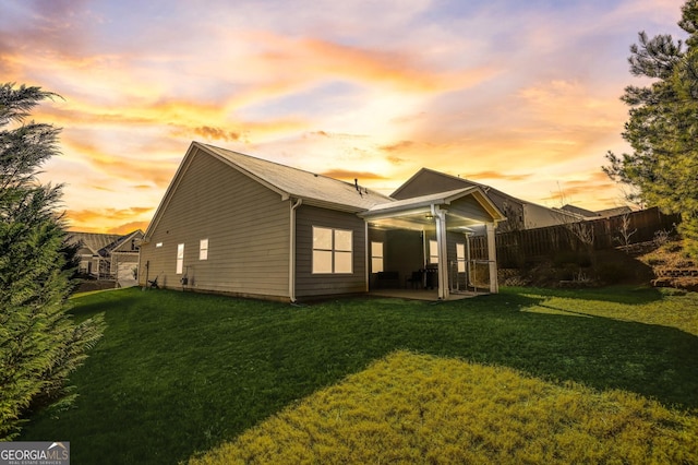 back house at dusk with a yard and a patio area