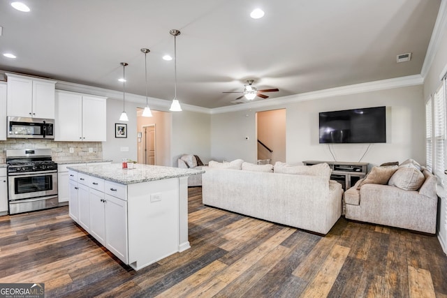 kitchen featuring a kitchen island, stainless steel appliances, hanging light fixtures, and white cabinetry