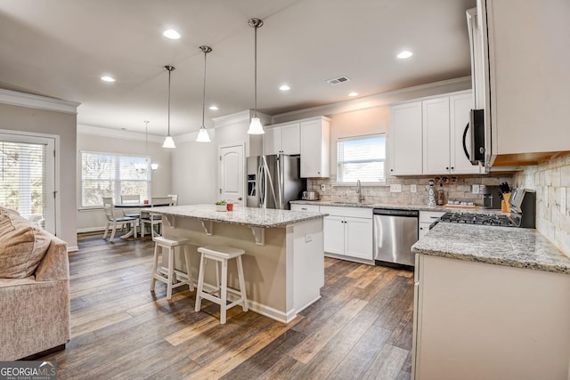 kitchen with white cabinets, plenty of natural light, dark wood-type flooring, appliances with stainless steel finishes, and a center island