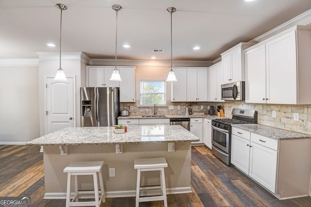 kitchen featuring a kitchen island, decorative light fixtures, white cabinetry, appliances with stainless steel finishes, and dark hardwood / wood-style floors