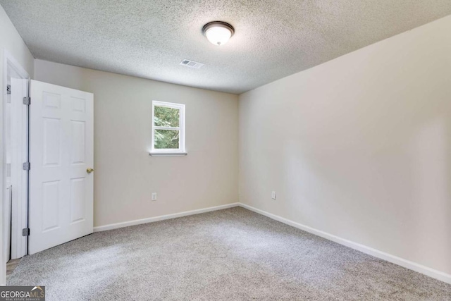 empty room with carpet floors and a textured ceiling