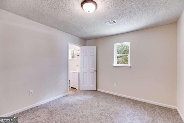 carpeted spare room with a textured ceiling