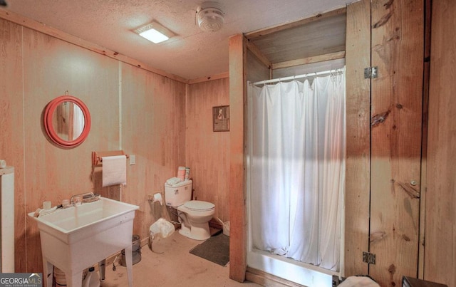 bathroom featuring sink, a textured ceiling, wooden walls, a shower with curtain, and toilet