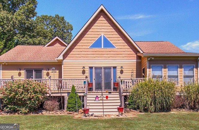 rear view of house with a deck and a yard