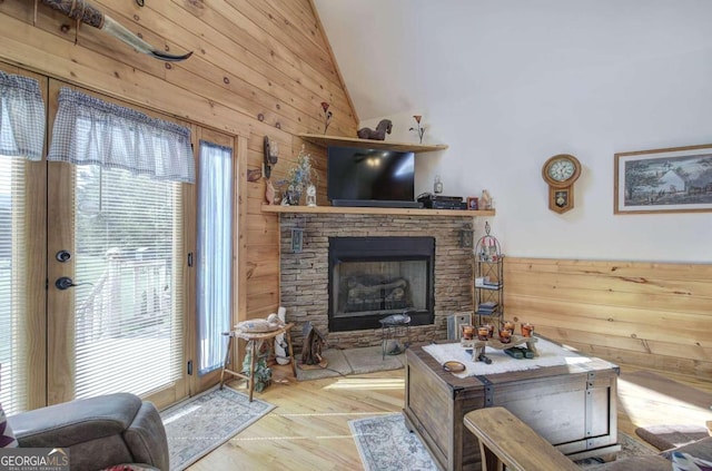 living room with light hardwood / wood-style flooring, wooden walls, and high vaulted ceiling